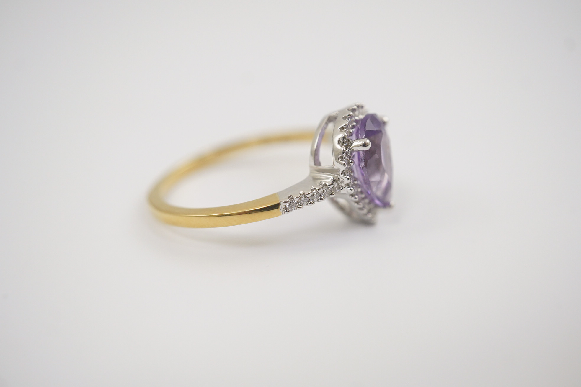 A modern 18ct gold and single stone pear cut amethyst set ring, with diamond chip set border and shoulders